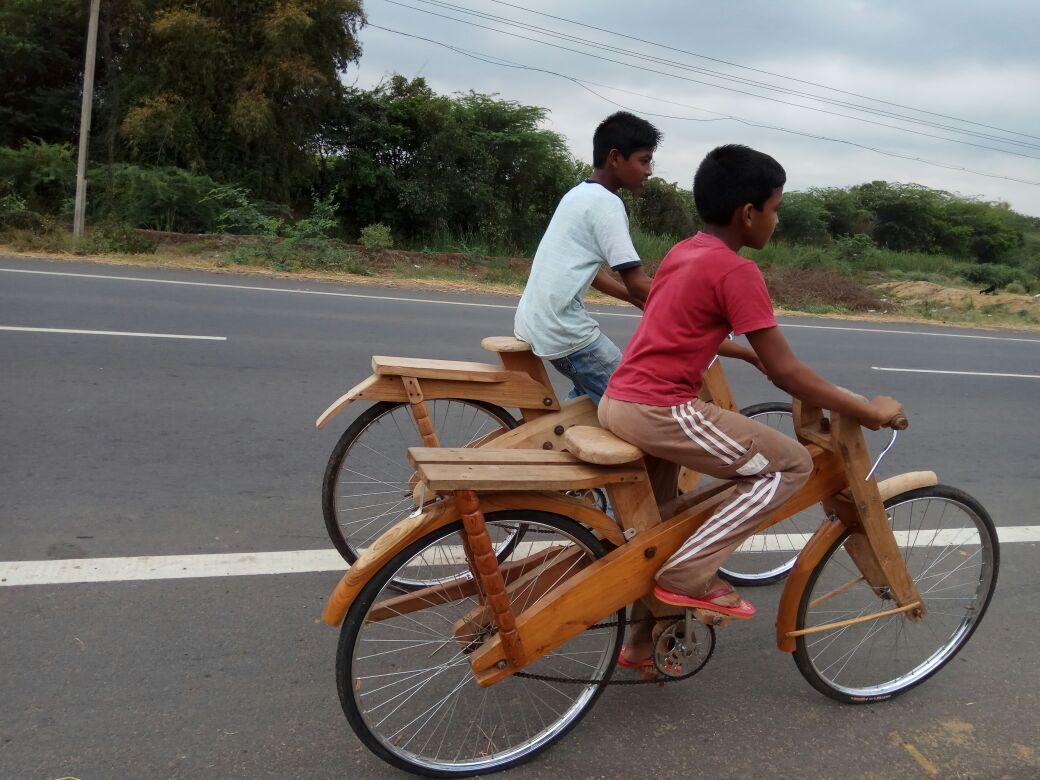 மர சைக்கிளை ஓட்டும் சிறுவர்கள்